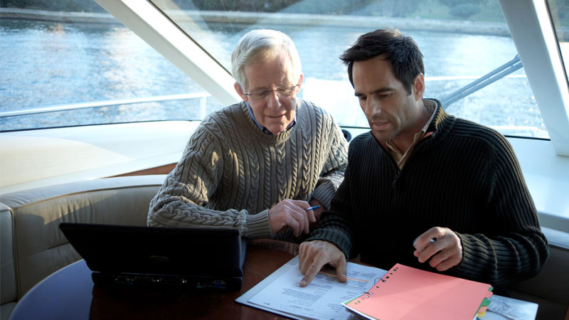 Zwei Männer sitzen auf einem Boot und besprechen die Finanzen